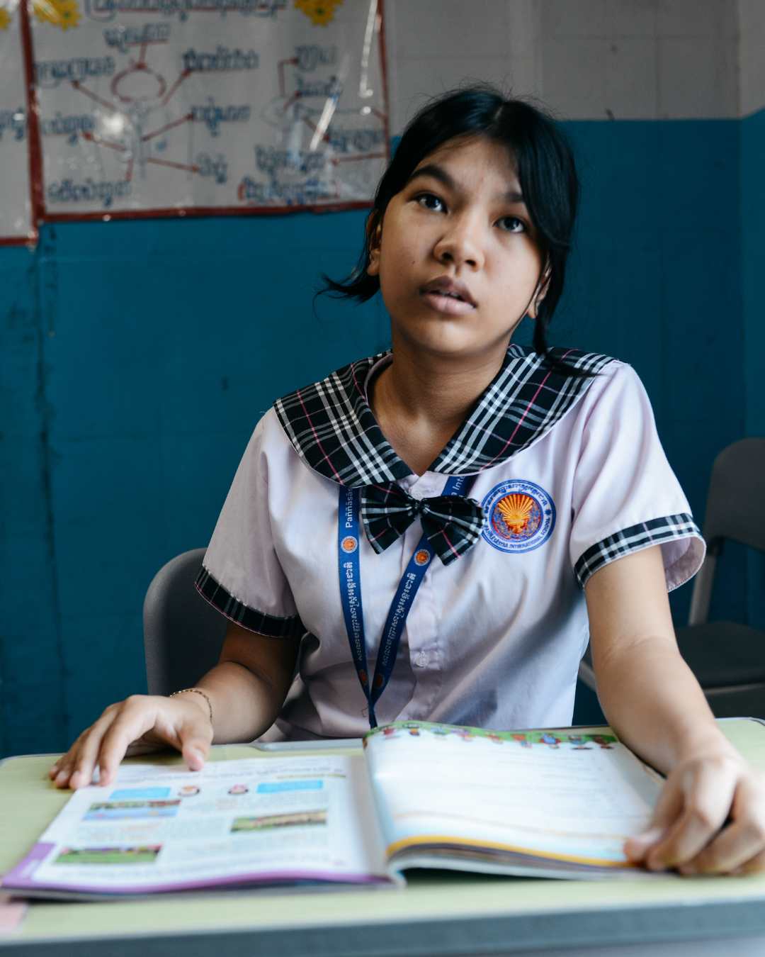 A smiling student holds a Hagar workbook