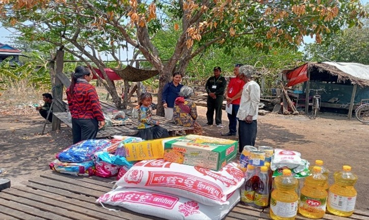 Staff visit a family while household supplies are arranged outdoors