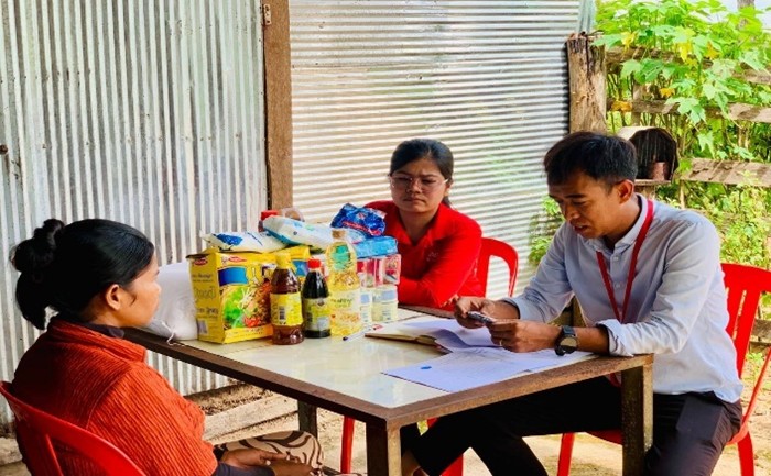 Staff meet with a woman at a table beside household supplies